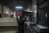Cesar Ambrosio helps his father carry a coffin at the Bergut Funeral Services factory in Santiago, Chile, Thursday, June 18, 2020. Coffin production has had to increase up to 120%, according to Nicolas Bergerie, owner of the factory. His more basic coffin model is called the COVID model and is made to cope with the increase of deaths during the coronavirus pandemic. (AP Photo/Esteban Felix)