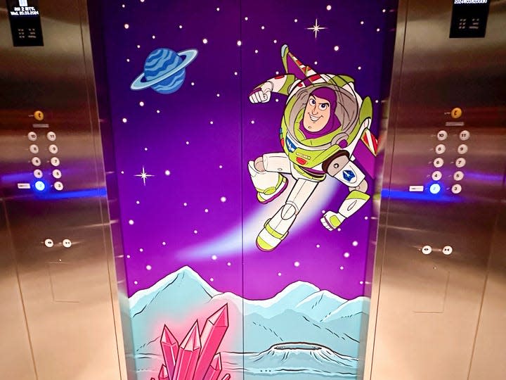 A shot of the inside of elevator doors at the Toy Story Hotel in Tokyo showing a Buzz Lightyear cartoon flying in space.