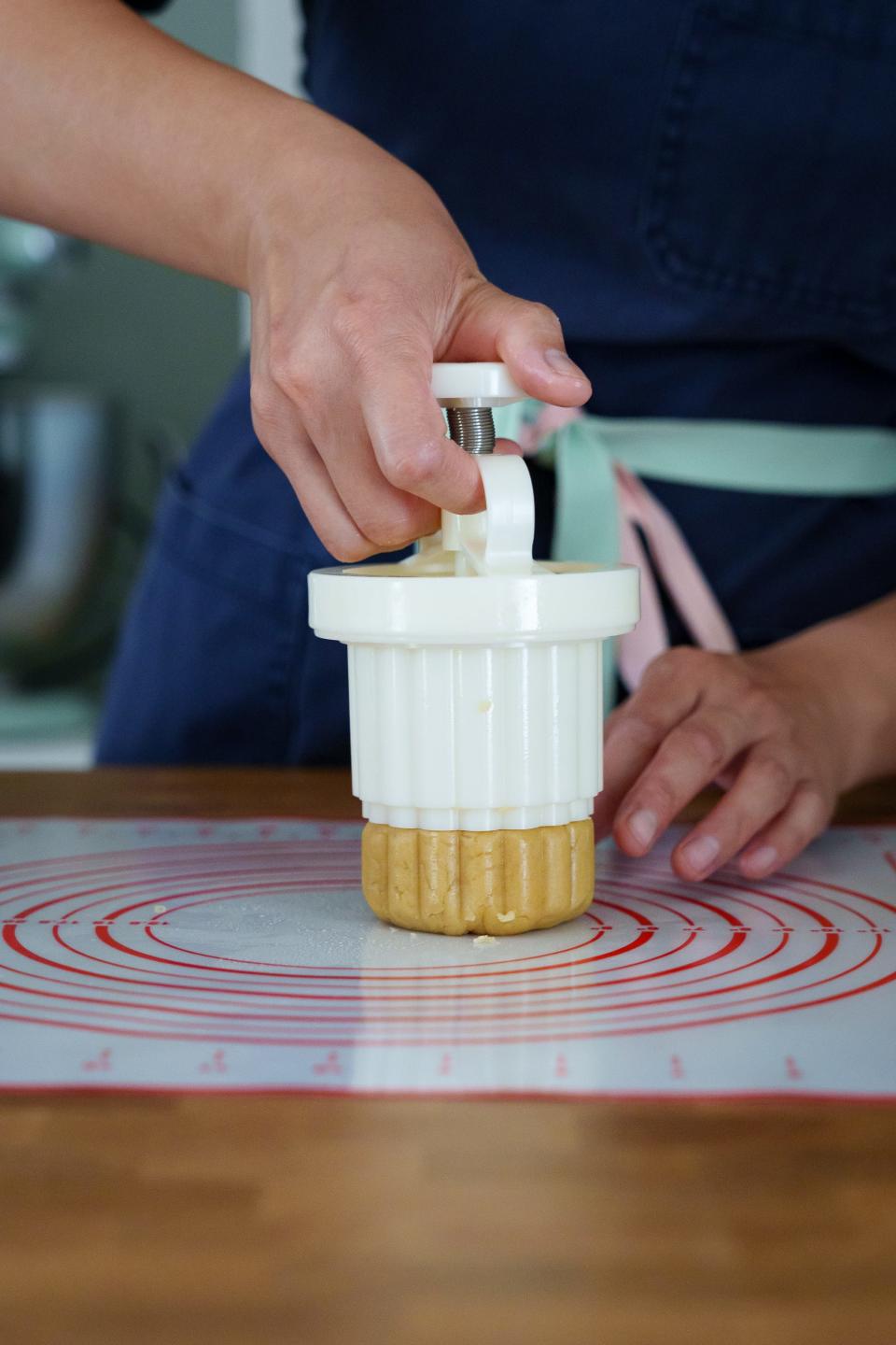 Alex Layshock demonstrates for The Arizona Republic by pressing her mooncake dough in a mold on May 7, 2023, in Phoenix.