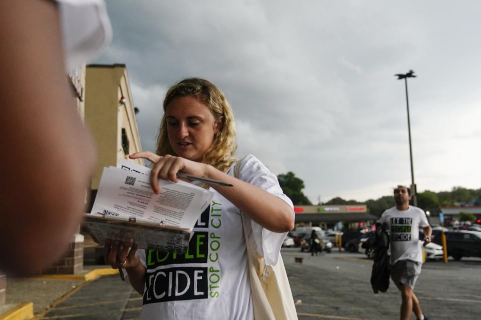 Canvasser Sienna Giraldi, 26, right, talks to an Atlanta resident, left, Thursday, July 20, 2023, in Atlanta. Activists with the Stop Cop City Vote Coalition are trying to get the signatures of more than 70,000 Atlanta residents by Aug. 14 to force a referendum allowing voters to decide the fate of a proposed police and firefighter training center. (AP Photo/Brynn Anderson)