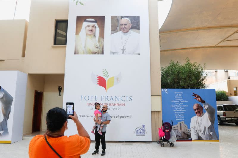 FILE PHOTO: A visitor take photo in front of welcome banner for Pope Francis at Sacred Heart Catholic Church in Manama