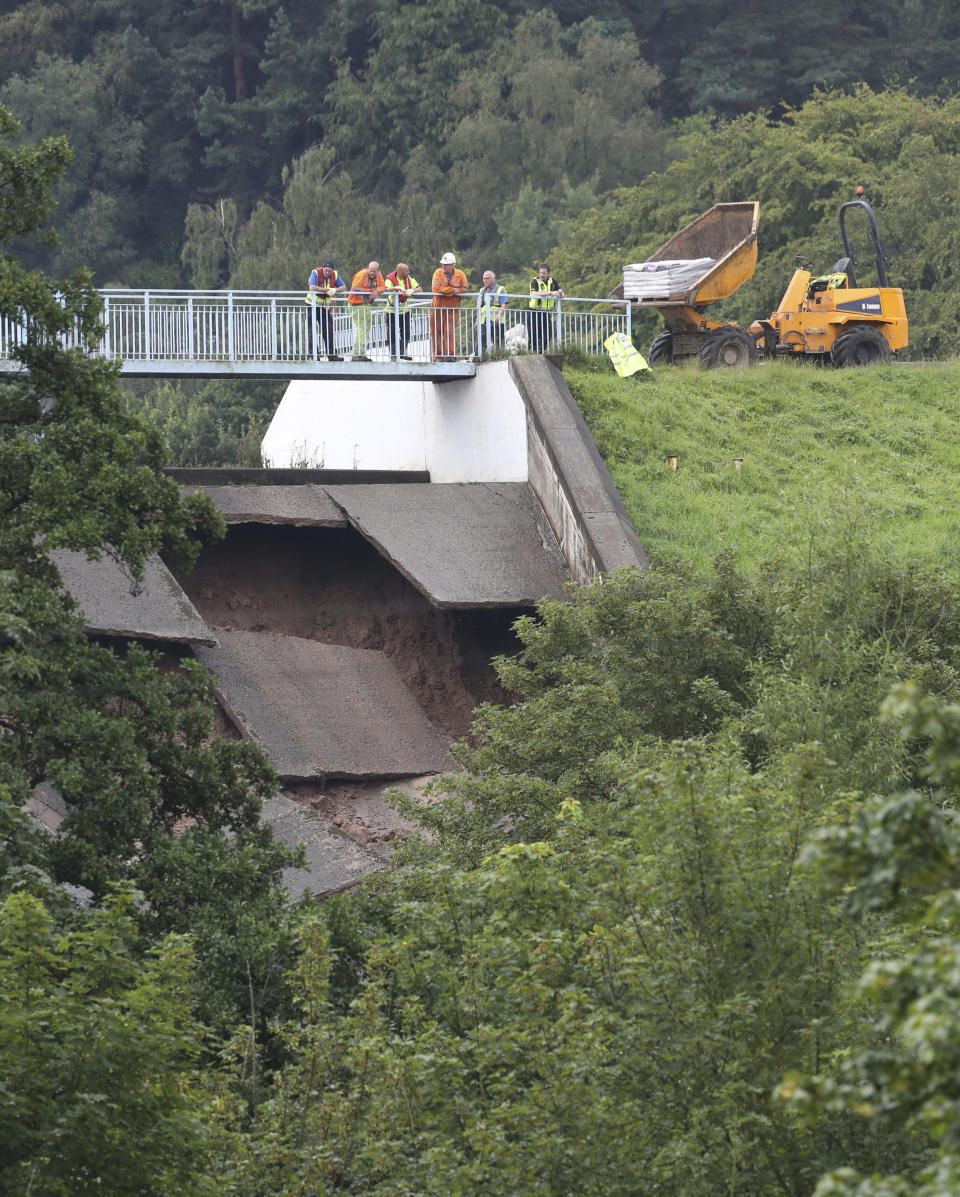 A team of men look at the damage to the wall of Toddbrook Reservoir near the village of Whaley Bridge, Cheshire, England, Thursday, Aug. 1, 2019. British police have ordered the evacuation of a town of 6,500 residents in northwest England over fears that a dam could collapse. The Derbyshire Police force says residents of Whaley Bridge should leave their homes because of the "significant threat to life." (Danny Lawson/PA via AP)