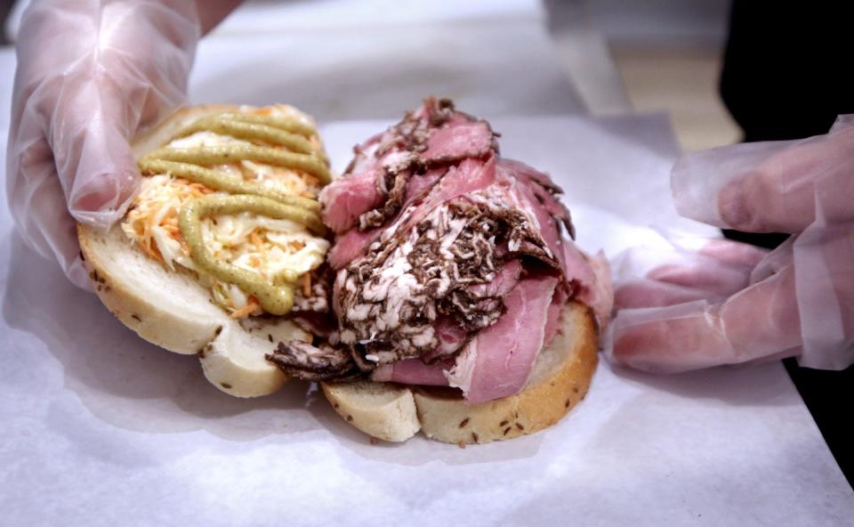 Jeffery Ingber finishes preparing a corned beef and pastrami sandwich in the deli at Bubbie's Market and Deli on Hope Street in Providence.