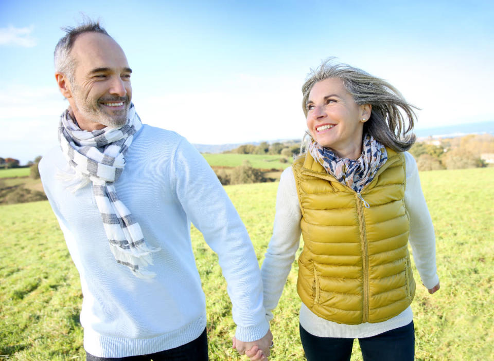 happy older couple walks in grassy area