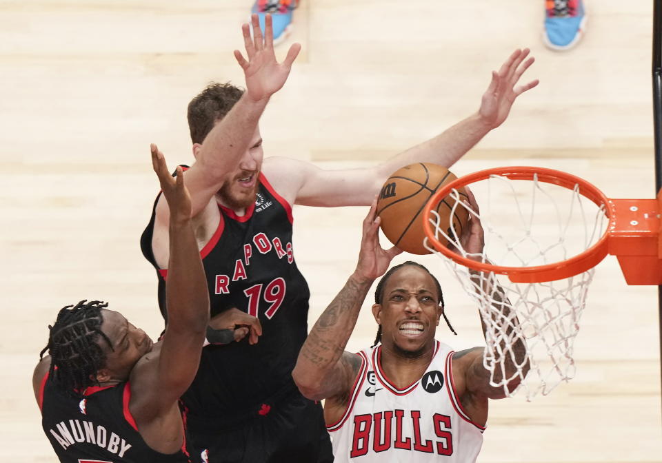 DeMar DeRozan, alero de los Bulls de Chicago, salta para encestar frente a O.G. Anunoby y Jakob Poeltl (19) de los Raptors de Toronto, el miércoles 12 de abril de 2023 (Nathan Denette/The Canadian Press via AP)