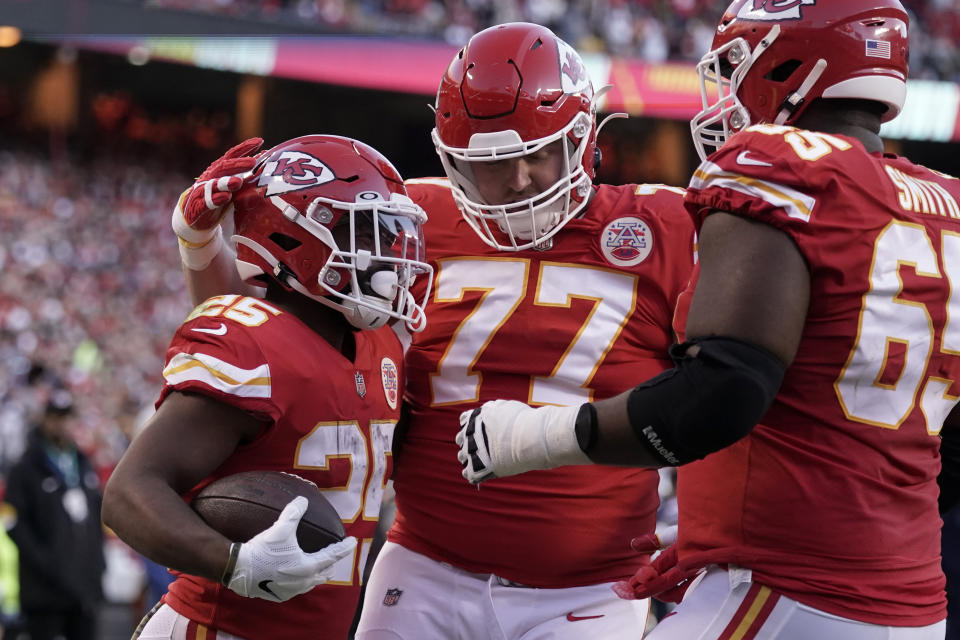 Kansas City Chiefs running back Clyde Edwards-Helaire, left, is congratulated by Andrew Wylie (77) and Trey Smith (65) after scoring during the first half of an NFL football game against the Dallas Cowboys Sunday, Nov. 21, 2021, in Kansas City, Mo. (AP Photo/Charlie Riedel)