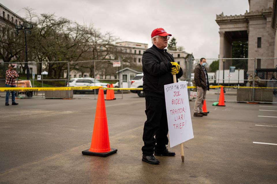 A Trump supporter holds a sign that reads "Stop The Steal! Joe Biden Traitor! Liar! Thief!" in front of the Washington State Capitol on Sunday, Jan. 17, 2021, in Olympia, Washington.