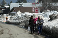Two women carry food and supplies from a nearby distribution center after a series of storms Wednesday, March 8, 2023, in Crestline, Calif. Residents of Southern California mountain towns are still struggling to dig out and get necessities in the aftermath of a record-setting blizzard last month that dumped so much snow that roads became impassable and roofs collapsed. (AP Photo/Marcio Jose Sanchez)