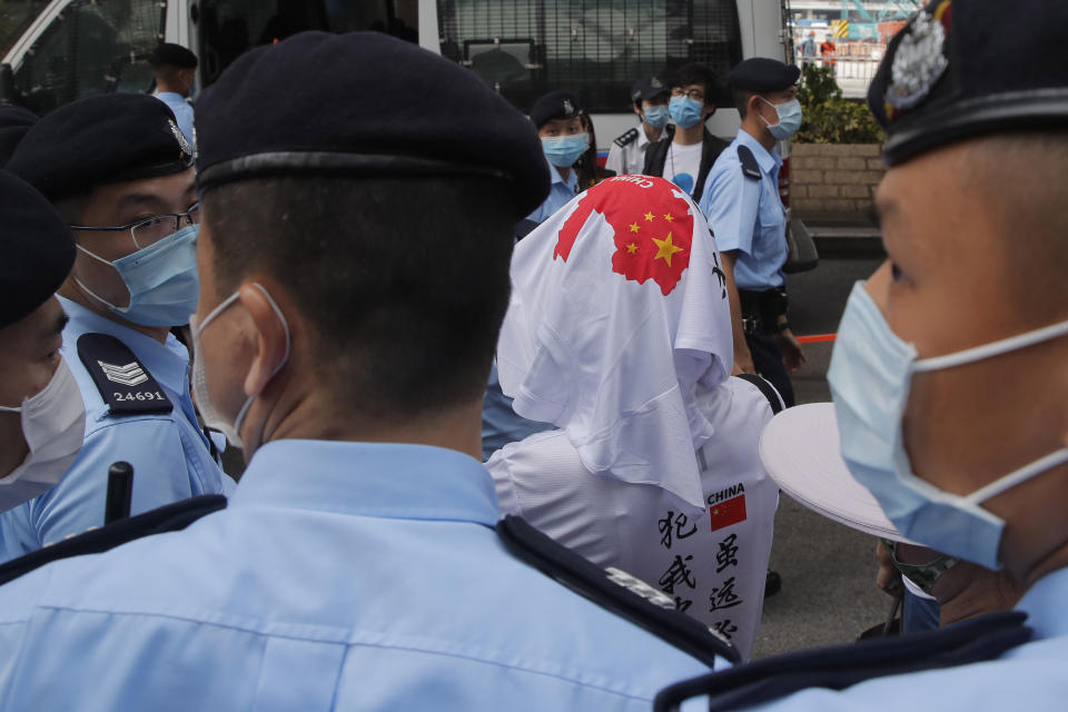 Pro-China activists are escorted by police officers as they argue with pro-democracy protesters outside a court during a protest in Hong Kong, Thursday, Aug. 27, 2020. Hong Kong police arrested 16 people, including two opposition lawmakers, on Wednesday on charges related to anti-government protests last year. (AP Photo/Kin Cheung)