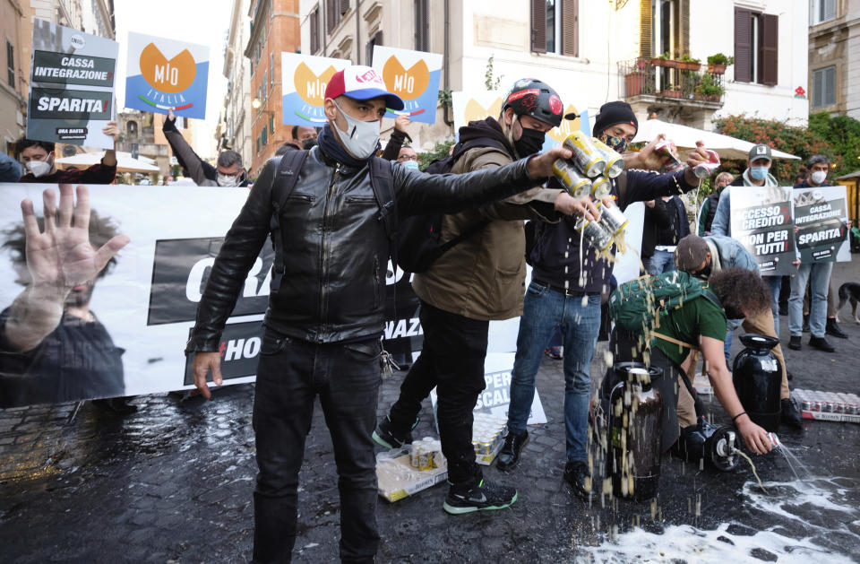 People spill beer on the ground during a protest against the government restriction measures to curb the spread of COVID-19, in Rome, Saturday, Oct. 24, 2020. Italian Premier Giuseppe Conte, who imposed severe-stay-at-home limits on citizens early on, then gradually eased travel and other restrictions, has been leaving it up to regional governors in this current surge of infections to order restrictions such as overnight curfews, including in places like Rome, Milan and Naples. (Mauro Scrobogna/LaPresse via AP)