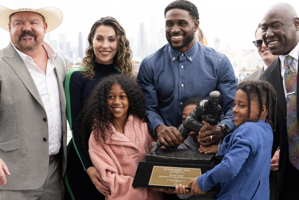 Former USC football player Reggie Bush poses with his attorneys, his family and his Heisman trophy at the Los Angeles Memorial Coliseum. (AP Photo/Richard Vogel)