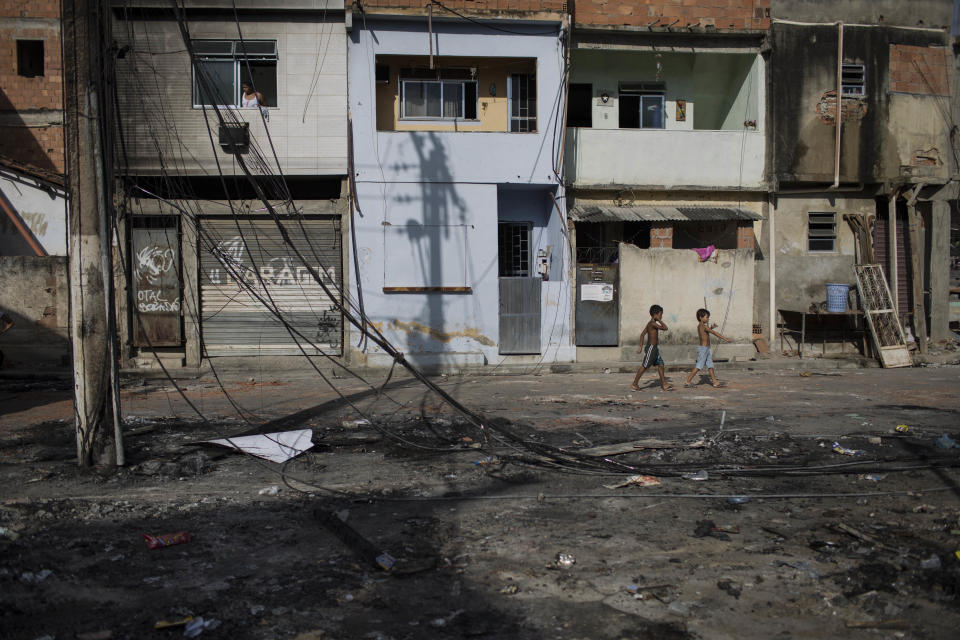 Children walk past what remains of a Pacifying Police Unit post at the Mandela shantytown, part of the Manguinhos slum complex, in Rio de Janeiro, Brazil, Friday, March 21, 2014. Rio de Janeiro police say suspected drug gang members on Thursday night attacked three police slum outposts and burned one of them. Officials say they'll ask for elite Brazilian federal police to help quell a wave of violence in supposedly pacified slums. (AP Photo/Felipe Dana)