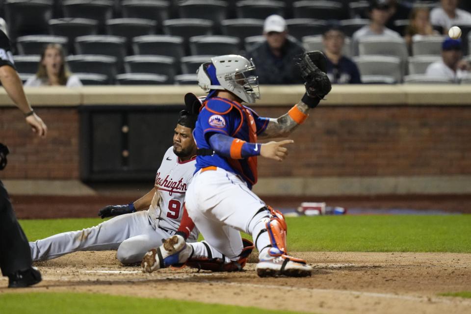 Washington Nationals' Jeimer Candelario (9) slides past New York Mets catcher Francisco Alvarez to score on a single by Joey Meneses during the ninth inning of a baseball game Saturday, July 29, 2023, in New York. (AP Photo/Frank Franklin II)