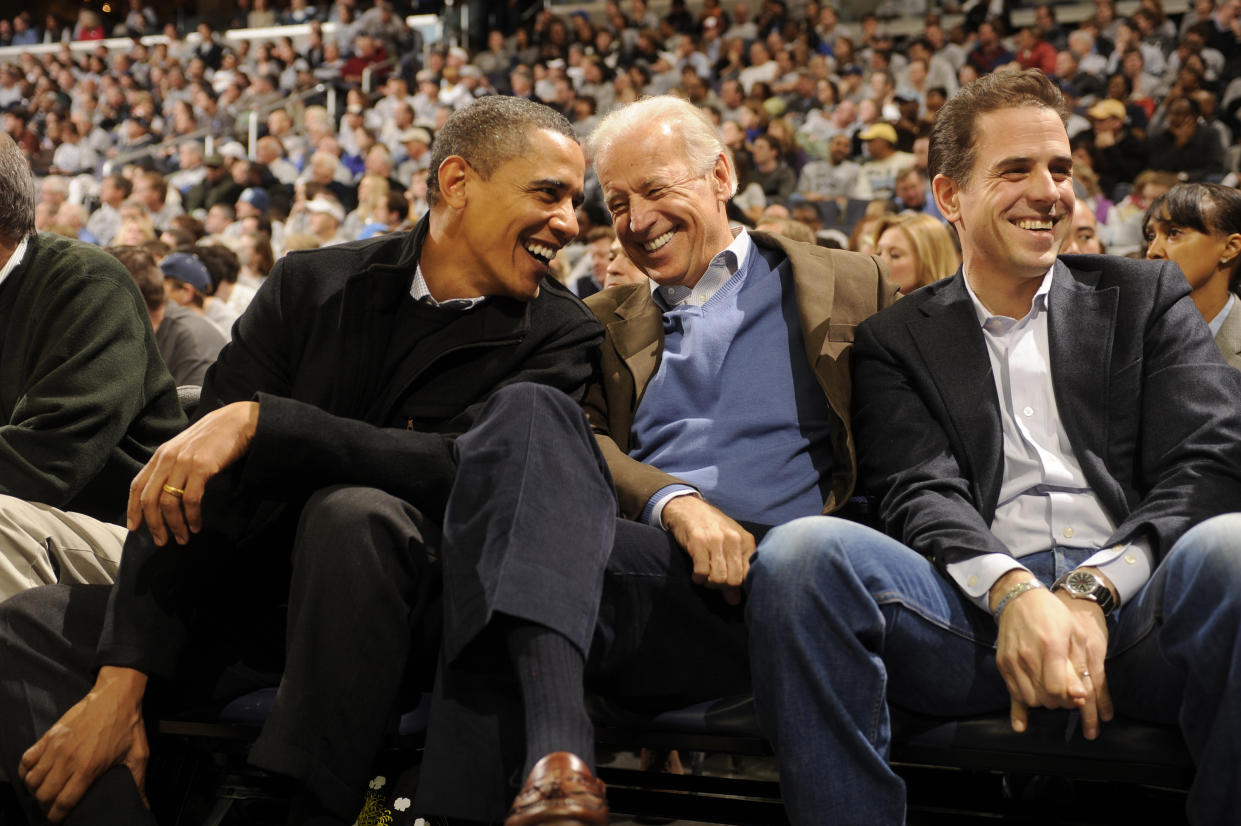 Barack Obama, then-Vice President Joe Biden and Hunter smile while seated in a crownd at a sports arena