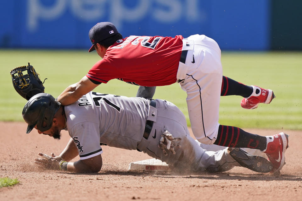 Chicago White Sox's Jose Abreu, bottom, is safe at second base as Cleveland Indians' Yu Chang lets the ball get by in the sixth inning of the first baseball game of a doubleheader, Monday, May 31, 2021, in Cleveland. Indians' Cesar Hernandez was charged with a throwing error. (AP Photo/Tony Dejak)