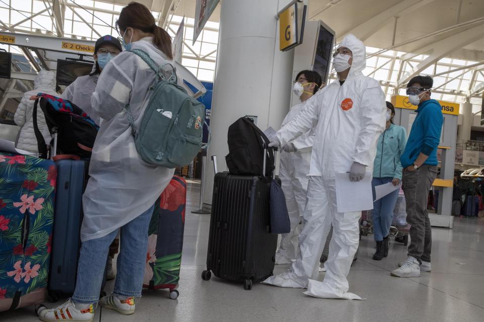 Passengers wear safety gear to fend off coronavirus as they wait in line to check in for their flights, Tuesday, March 24, 2020, at JFK airport in New York.