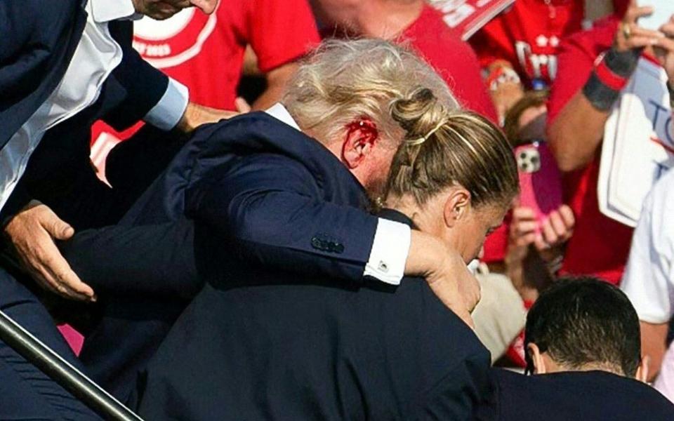 Donald Trump is seen with blood on his face surrounded by secret service agents