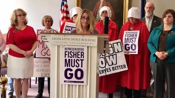 A sexual assault survivor with handmaids demanding Rep. Robert Fisher's resignation, on May 17, 2017, in Concord, N.H.