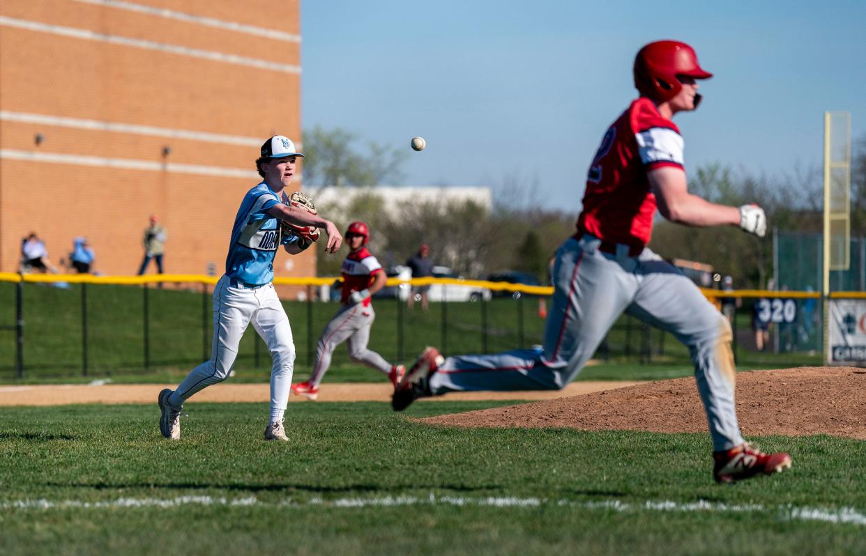 North Penn's Chris Bennis (13) throws to first as Neshaminy's Ryan Fox (12) runs toward the base.