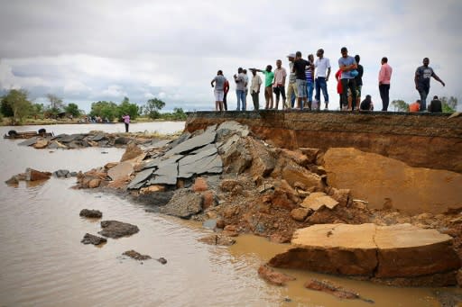 People stand beside a damaged section of the road between Beira and Chimoio in Nhamatanda district, central Mozambique