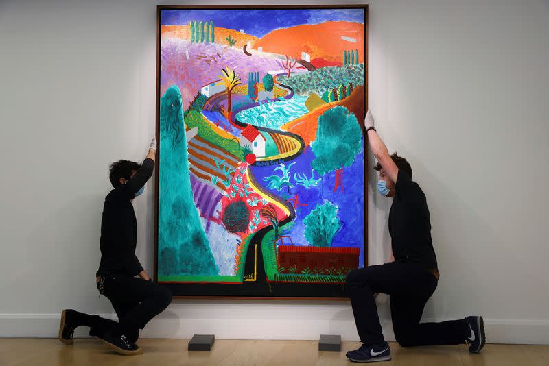 Employees adjust a painting by David Hockney entitled 'Nichols Canyon' which has an estimated value of $35 million at Phillips auction house in London