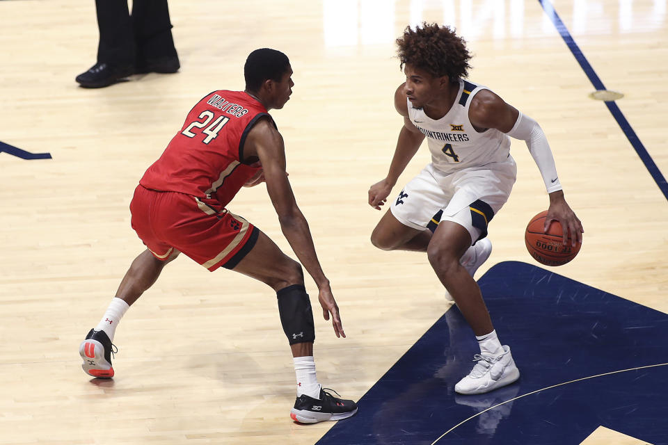 West Virginia guard Miles McBride (4) is defended by Northeastern guard Shaquille Walters (24) during the first half of an NCAA college basketball game Tuesday, Dec. 29, 2020, in Morgantown, W.Va. (AP Photo/Kathleen Batten)