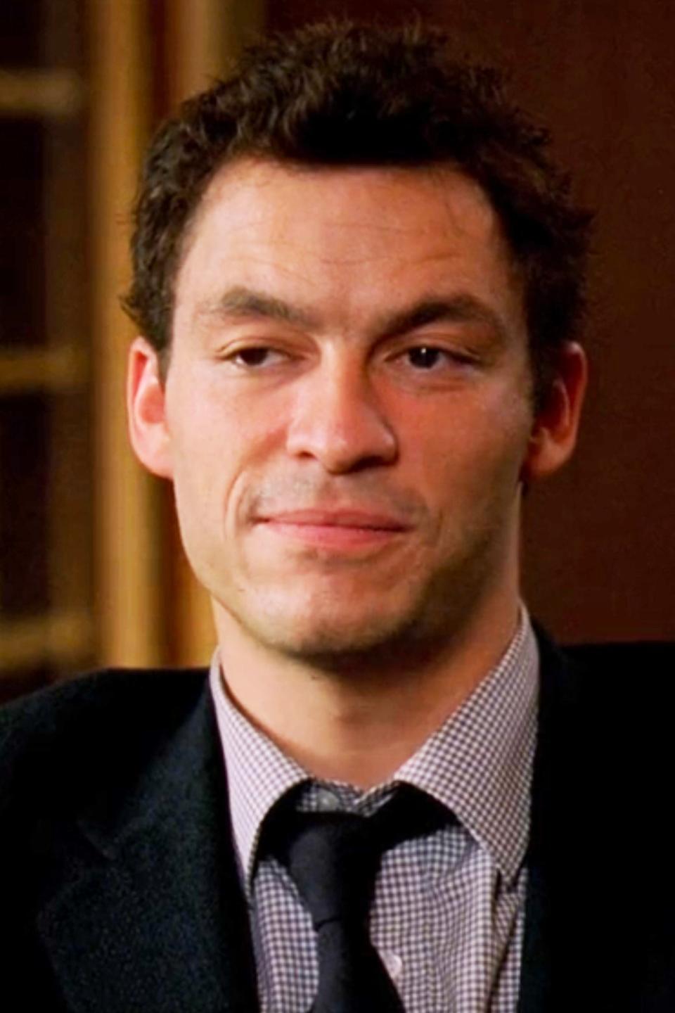 A young Dominic West wearing a suit in a scene from 