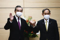 Japan's Prime Minister Yoshihide Suga, right, bumps fists with China's Foreign Minister Wang Yi at the start of their meeting in Tokyo, Wednesday, Nov. 25, 2020. (Behrouz Mehri/Pool Photo via AP)