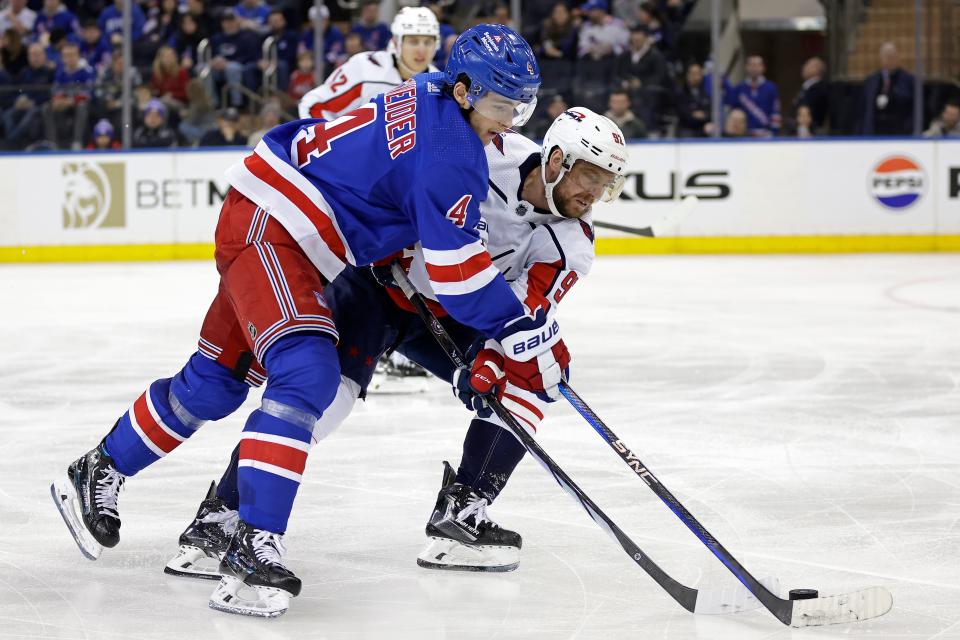 New York Rangers defenseman Braden Schneider (4) works for the puck against Washington Capitals center Evgeny Kuznetsov during the third period of an NHL hockey game Wednesday, Dec. 27, 2023, in New York.