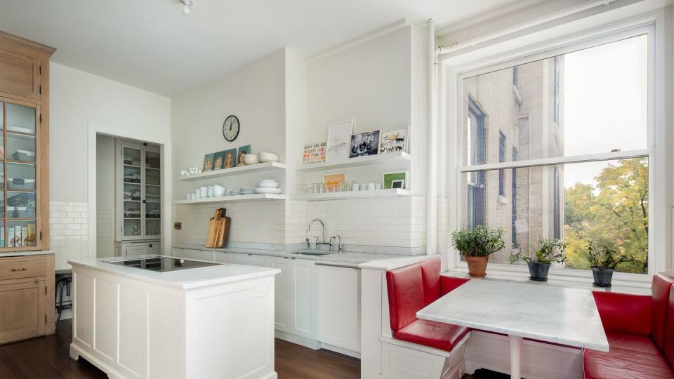 a kitchen with a white table and red chairs