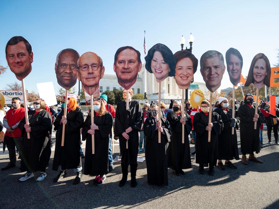 Pro-abortion activists hold cutout signs with the faces of Supreme Court justices outside the Supreme Court in December 2021.