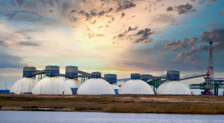 Several natural gas tanks with a sunrise in the background