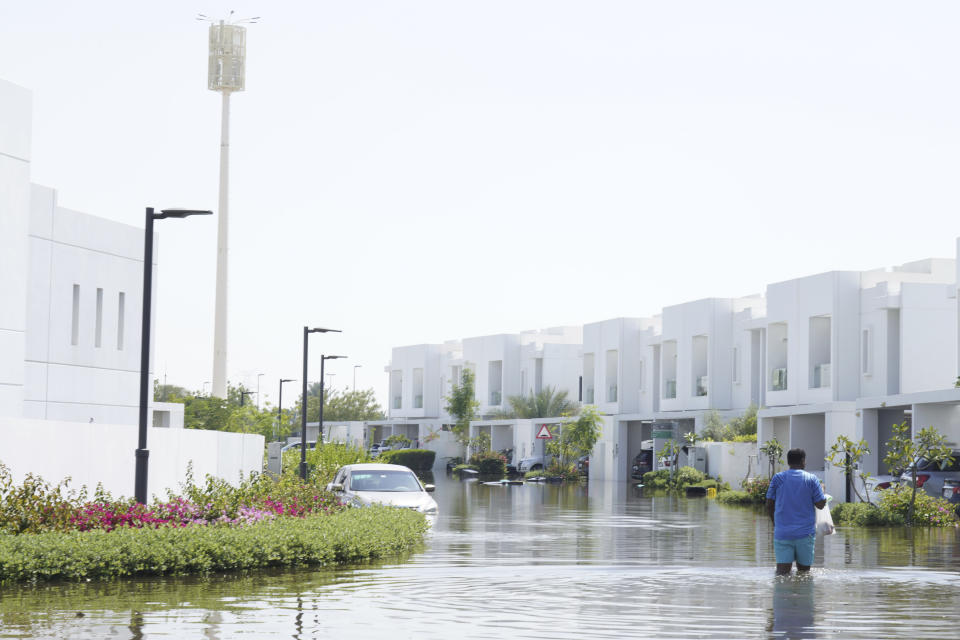 A man walks through floodwater in the Mudon neighborhood in Dubai, United Arab Emirates, Thursday, April 18, 2024. The United Arab Emirates attempted to dry out Thursday from the heaviest rain the desert nation has ever recorded — a deluge that flooded out Dubai International Airport and disrupted flights through the world's busiest airfield for international travel. (AP Photo/Jon Gambrell)