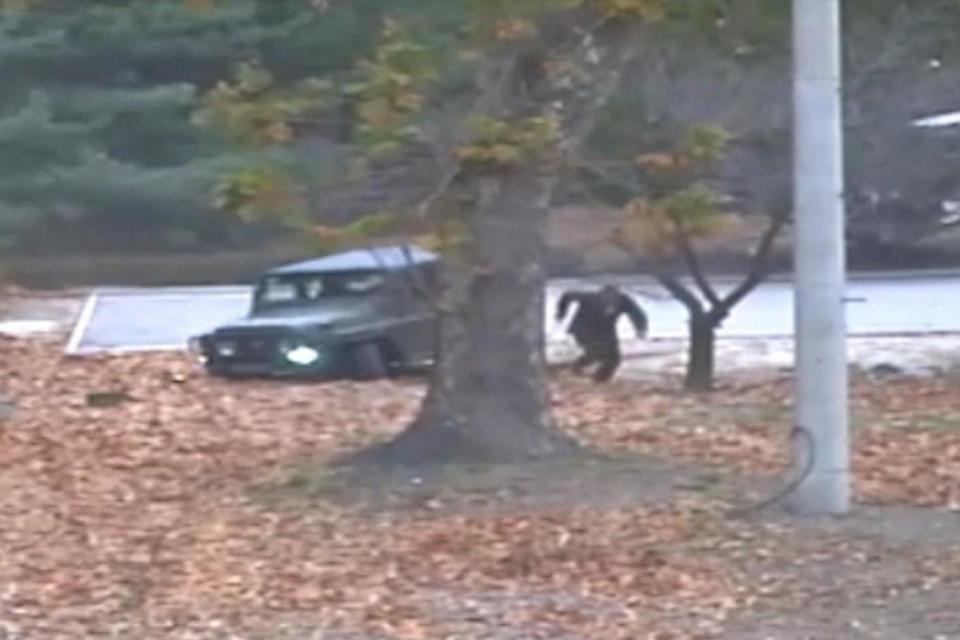 The defector can be seen running across fallen leaves after crashing the jeep (EPA)