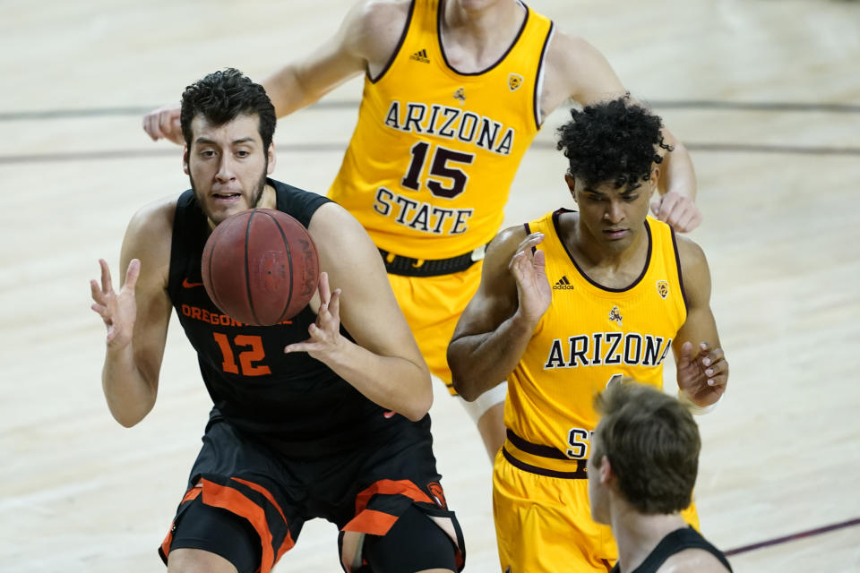 Oregon State center Roman Silva (12) is fouled by Arizona State guard Remy Martin as forward John Olmsted (15) looks on during the first half of an NCAA college basketball game, Sunday, Feb. 14, 2021, in Tempe, Ariz.(AP Photo/Matt York)