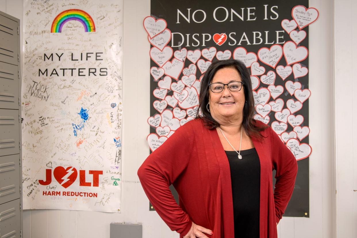 Dr. Tamara Olt, a veteran Peoria obstetrician and gynecologist, poses in front of a memorial wall for those lost to drug addiction at JOLT Harm Reduction in Peoria. At right is another poster featuring signatures of the many survivors and advocates of the nonprofit agency. Dr. Olt founded the organization after she lost her son Josh, then 16, to a heroin overdose in 2012. She is a 2024 USA TODAY Women of the Year honoree.