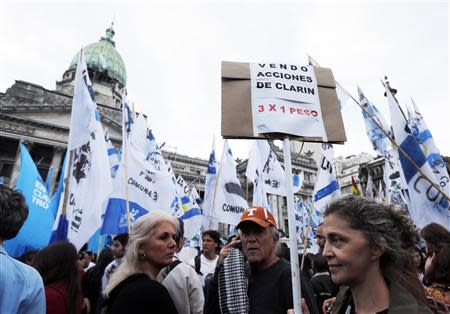 A pro-government demonstrator holds a sign that reads "I sell Clarin shares just three x one peso" outside the Congress building in Buenos Aires October 29, 2013. REUTERS/Enrique Marcarian