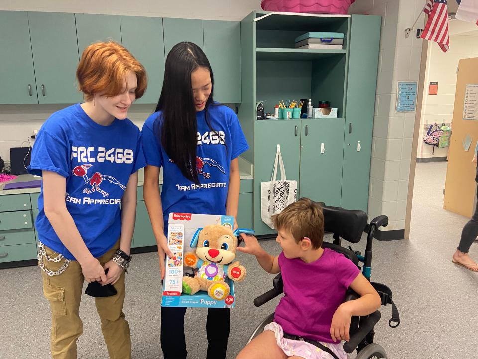 Adi McKaskle, left, and Alina Tang present an assistive technology toy to Charlotte Leahy at Bridge Point Elementary School. The Westlake High robotics team has been revamping toys to make them more accessible for students with disabilities.