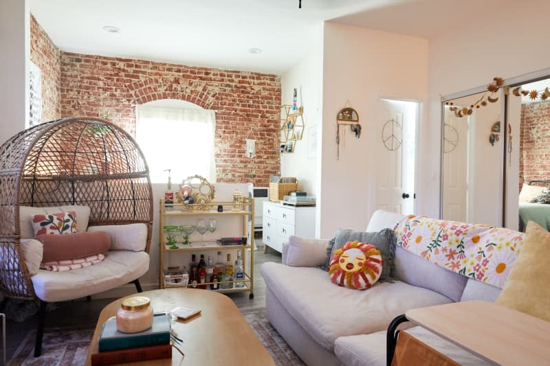 Brick-walled living room with white couch and decorative pillows.