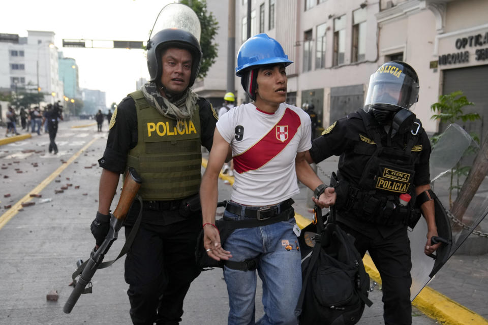 Police detain an anti-government protester in downtown Lima, Peru, Tuesday, Jan. 24, 2023. Protesters are seeking the resignation of President Dina Boluarte, the release from prison of ousted President Pedro Castillo, immediate elections and justice for demonstrators killed in clashes with police. (AP Photo/Martin Mejia)