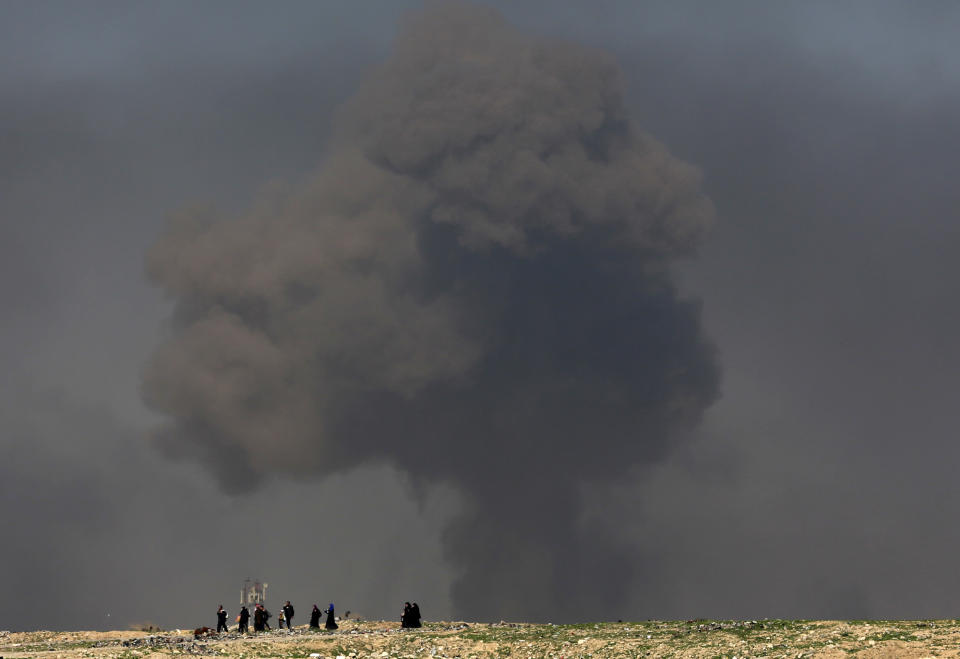 FILE - In this March 9, 2017 file photo, a large cloud of smoke rises during fighting between Iraqi security forces and Islamic State militants as civilians walk toward Iraqi security forces after fleeing their homes on the western side of Mosul, Iraq. The U.S. is deepening its involvement in the war against the Islamic State group after an unprecedented American airlift of Arab and Kurdish fighters to the front lines in northern Syria, supported by the first use of U.S. attack helicopters and artillery in the country. (AP Photo/Khalid Mohammed, File)