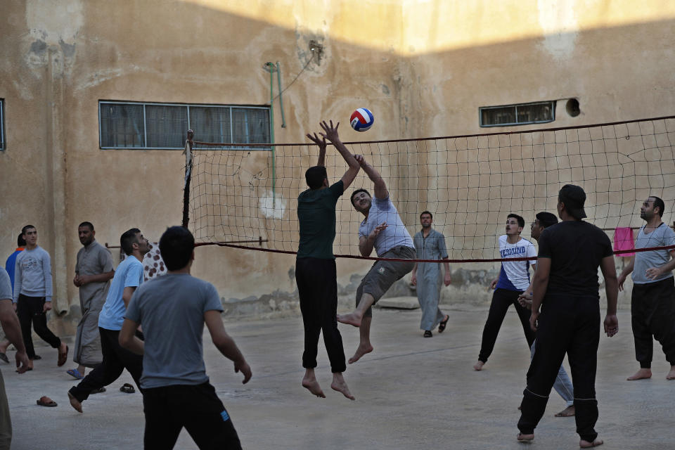 CAPTION ADDITION: ADDS DETAILS ABOUT WHICH PRISON HAD RIOTS: FILE - In this April 3, 2018, file photo, prisoners play volleyball in a Kurdish-run prison housing former members of the Islamic State group, in Qamishli, northern Syria. A spokesman for Kurdish-led forces in northeastern Syria said Monday, March. 30, 2020, that they have put an end to riots by Islamic State militants in a prison there. The riots broke out late on Sunday in a prison in the town of Hassakeh and lasted several hours. Kurdish authorities run more than two dozen detention facilities scattered around northeastern Syria, holding about 10,000 IS fighters. (AP Photo/Hussein Malla, File)