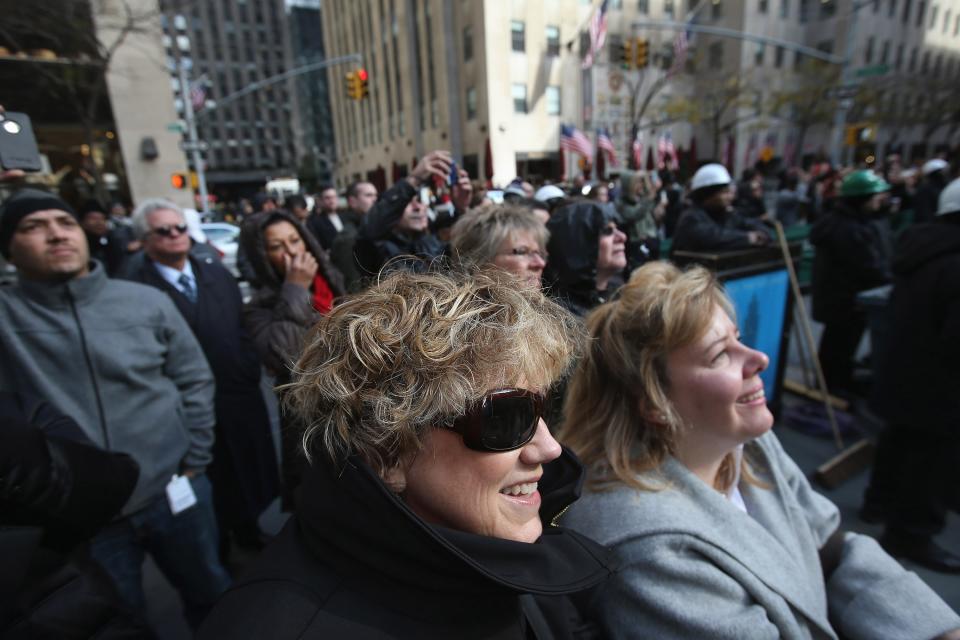 NEW YORK, NY - NOVEMBER 14: People watch as the Rockefeller Center Christmas tree is about to be raised into position on November 14, 2012 in New York City. The tree, an 80-year old Norway Spruce, was donated by Joe Balku of Flanders, New Jersey. It weighs approximately 10 tons, measures 80 feet tall and is 50 feet in diameter. The official tree-lighting ceremony will be Wednesday, November 28. (Photo by John Moore/Getty Images)