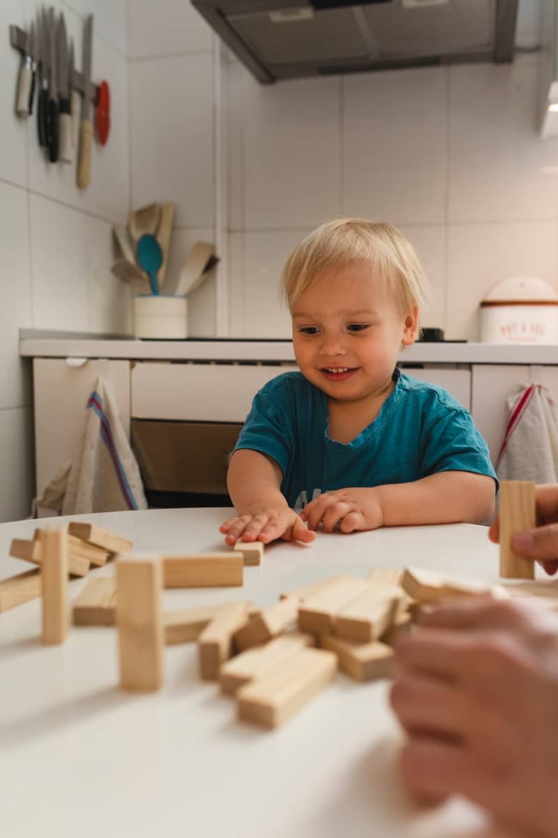 child playing jenga with family in kitchen