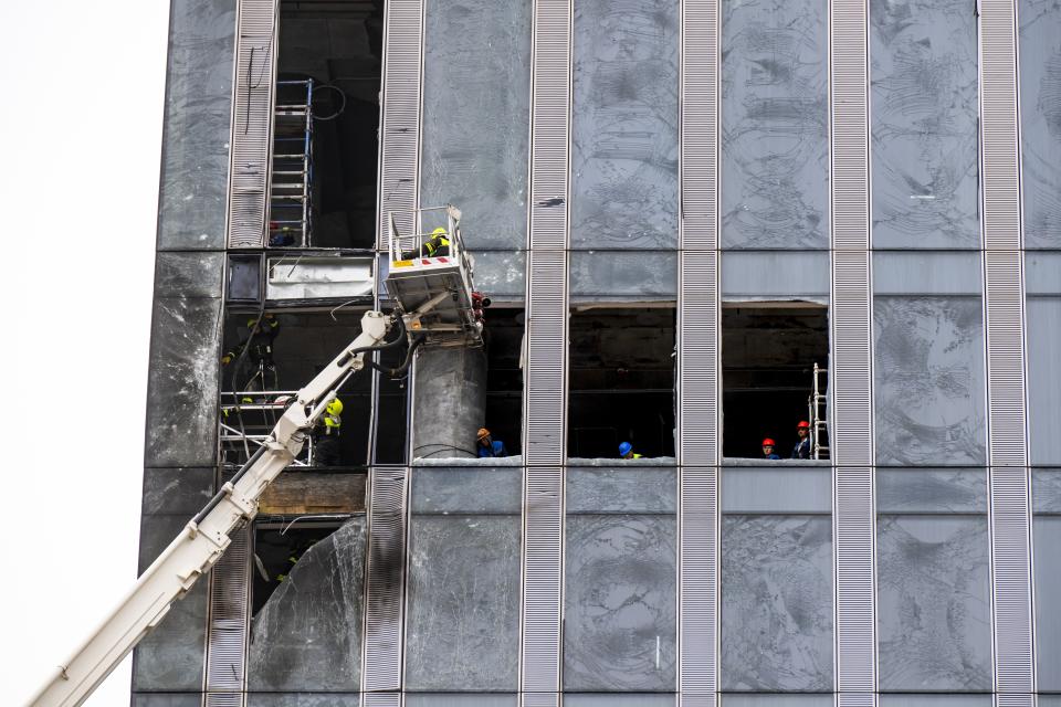 Workers clean a part of a damaged skyscraper in the 