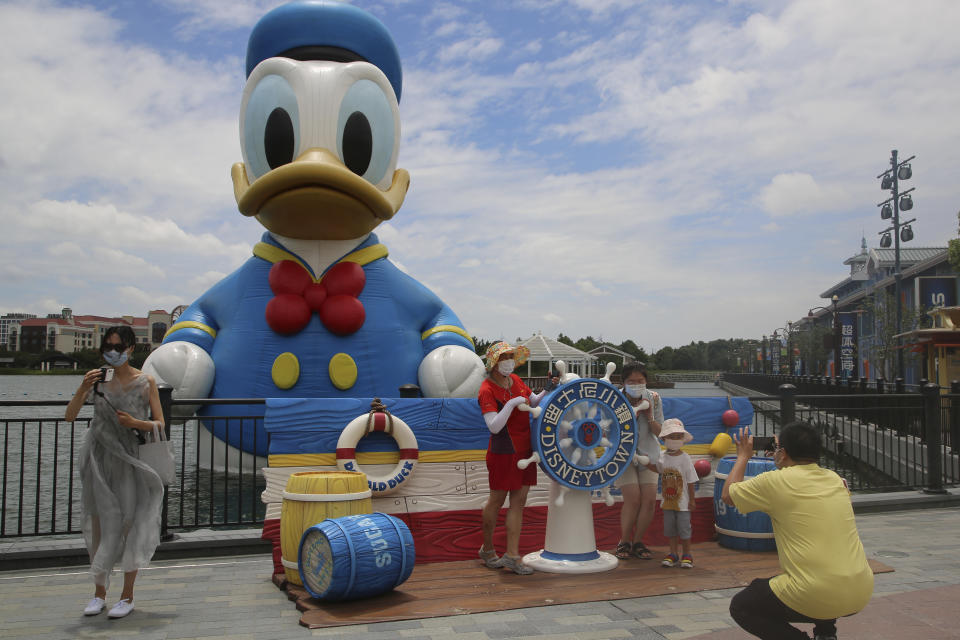 Visitors pose for photos outside the Disney Resort theme park, Thursday, June 30, 2022, in Shanghai. Shanghai is moving to allow in-person dining and reopening its Disney Resort theme park as domestically transmitted cases of COVID-19 in China's largest city remain at zero following a more than two-month lockdown. (AP Photo/Chen Si)