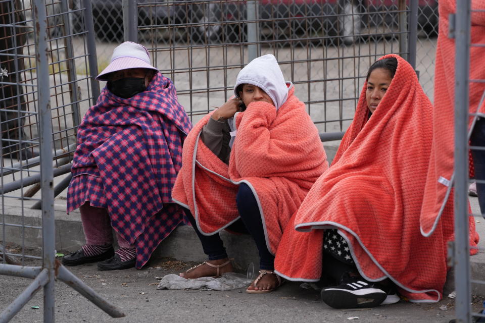 People with family and friends held inside Latacunga jail wait outside the facility for news after a deadly riot in Latacunga, Ecuador, Tuesday, Oct. 4, 2022. A clash between inmates armed with guns and knives inside the prison has left at least 15 people dead and 20 injured. (AP Photo/Dolores Ochoa)