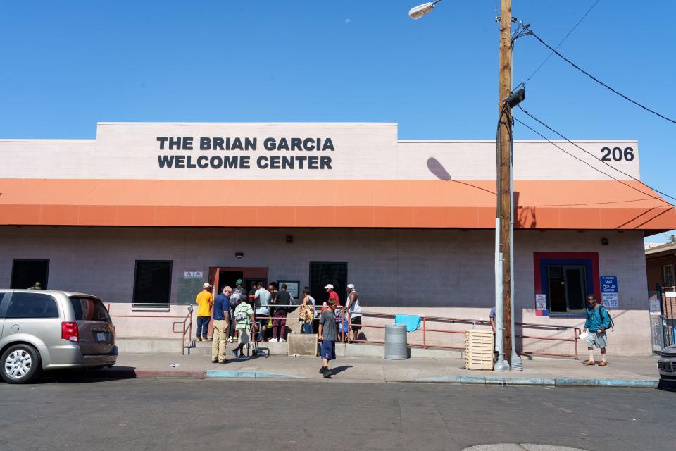 People line up at the Brian Garcia Welcome Center at the Human Services Campus, photographed on Aug. 7, 2023, in Phoenix. The building stands before the security gates, is open to the public and includes a walkup mail pick-up center.