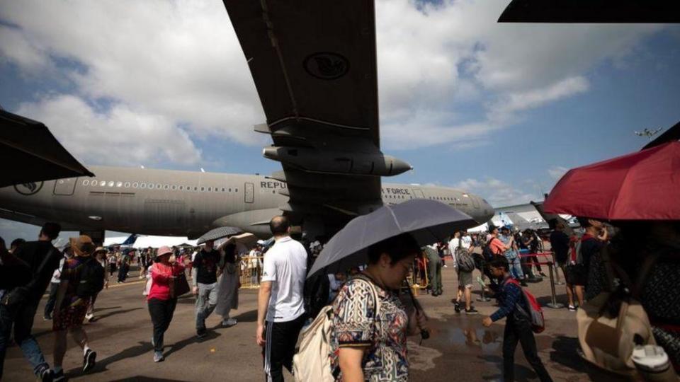 Un grupo de personas alrededor de un avión militar