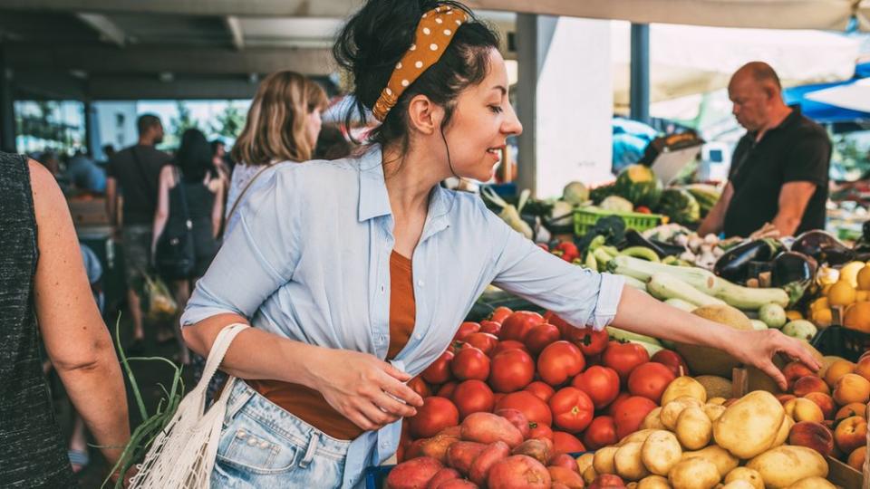 Mujer en un mercado sobre un puesto de patatas.